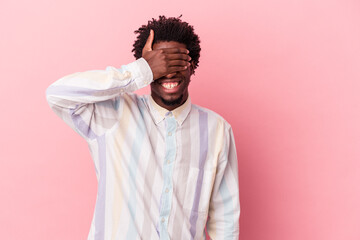 Young african american man isolated on pink background covers eyes with hands, smiles broadly waiting for a surprise.