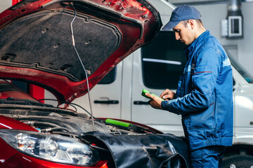 Car service electrician or mechanic uses a tablet computer with futuristic interactive diagnostics...