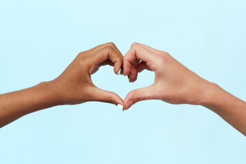 Caucasian and black african american woman showing heart gesture on blue background. Concept against racism, equality and unity, world peace.