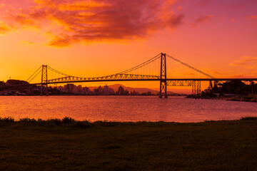 Hercilio luz cable bridge with bright sunset sky and reflection on water in Florianopolis