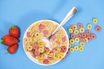 Quick breakfast cereal - rings with milk and strawberries on a blue background.