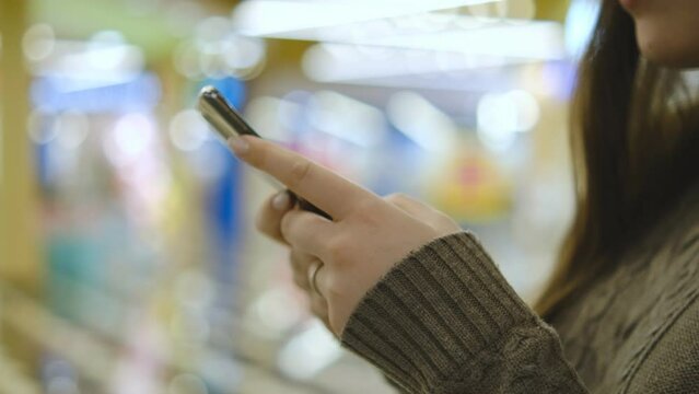 Shopping center. Moll. Finger of woman touching scroll page app on mobile phone. Browsing movie video in the internet library to watch film online.
