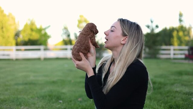 Pretty blonde female is kissing cute Goldendoodle puppy, then saying I love you.