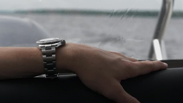 Rich and powerful man wearing expensive wristwatch control luxury yacht