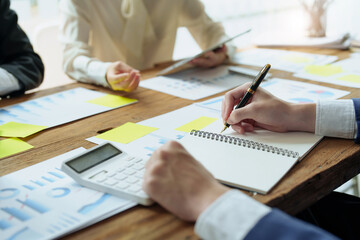 Male businessman holding pen to take notes summarizing marketing strategy with female colleagues in...
