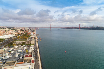 Aerial view of the promenade by Belem touristic area on the Tagus river with sailing boat dock of Belem and the 25th of April Bridge in the background