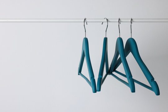 Blue clothes hangers on metal rail against light background. Space for text