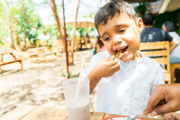 Latin boy eating pork belly or chicharron in a country restaurant in Managua Nicaragua