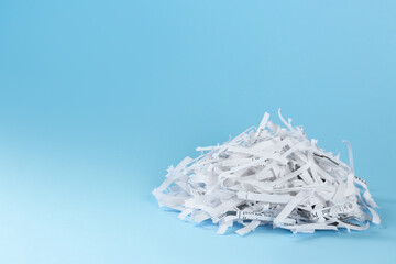 Heap of shredded paper strips on light blue background, space for text