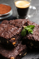 Delicious chocolate brownies with nuts and fresh mint on slate, closeup