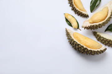 Pieces of fresh ripe durian and leaves on white background, flat lay. Space for text