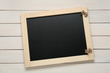 Obraz premium Clean small black chalkboard on white wooden table, top view