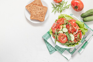 Fresh vegetable salad and wholegrain bread on a white backgound. Copy space. Top view. Healthy eating concept.