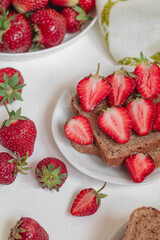French toast with sliced strawberris and wholegrain bread on a white plate.
