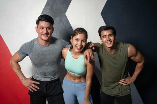 Sporty group of diverse friends in sportswear standing arm in arm smiling takes picture together after exercise in fitness gym