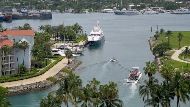 View of yachts, boats, and condos at Atlantis resort marina.  Boats head to sea through harbor channel.