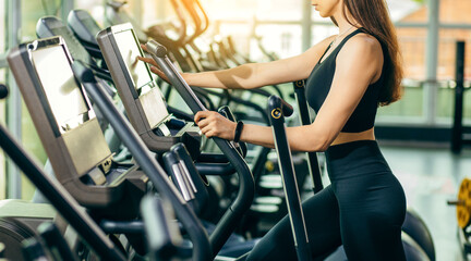 Fototapeta na wymiar Portrait of fitness young woman in sports clothing exercising on cardio machine at gym