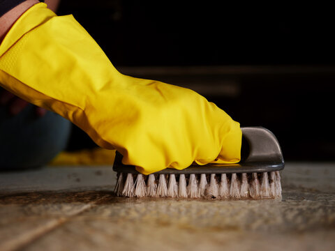 Woman scrubbing dirty floor with brush medium shot