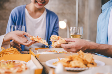 hands of a colleague or friend eating pizza After meeting at the office for a long time They're partying at home, eating pizza and having fun. food and drink people and holidays