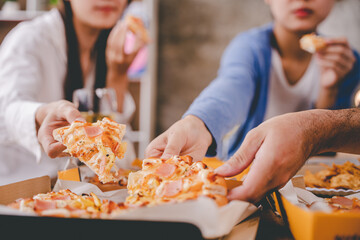 hands of a colleague or friend eating pizza After meeting at the office for a long time They're partying at home, eating pizza and having fun. food and drink people and holidays