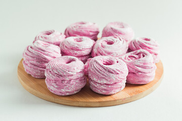 Pink marshmallow in the wooden plate on the white background
