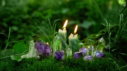 Minerals and candles close up in mysterious forest, dark natural background. Witchcraft, Esoteric...