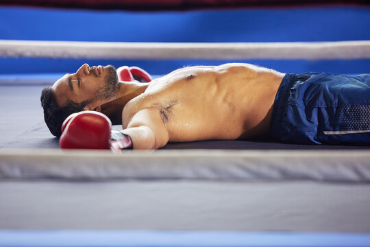 Looks like a knockout. Cropped shot of a handsome young male boxer lying in the ring with his eyes closed after a fight. - Powered by Adobe
