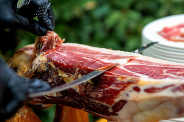 Master slicer taking iberian cured ham with tongs