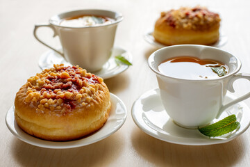 Sweet donuts on plates and cups with mint tea on the wooden table. Tasty breakfast.