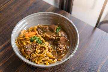 selective focus, Tagliatelle with pork stew and vegetables in a bowl served on wooden table, Spaghetti Pasta with meat.