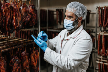 Experienced middle age man working in fresh meet processing plant. Industrial slaughterhouse worker...