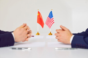 Flags of America and China atand on table during talks between diplomats and businessmen. American...