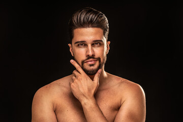 Handsome sensual man with brown eyes posing shirtless on black studio background. Muscular body.