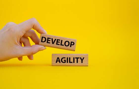 Develop agility symbol. Concept word Develop agility on wooden blocks. Beautiful yellow background. Businessman hand. Business and Develop agility concept. Copy space