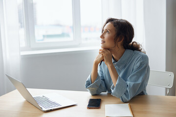 Dreaming adorable cheerful lovely enjoyed love mood reclines on folded hands looks aside at window remembers pleasant moments with her boyfriend last weekend sitting at light home modern office