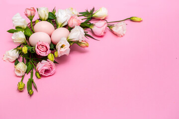 Easter background with Easter eggs and spring flowers. Top view with copy space. Nest with eggs decorated with beautiful flowers on a pink background.