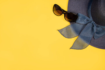 Beach accessories on pastel yellow background - hat and sunglasses with space for text, logo and...