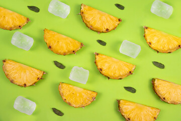 pineapple slices accompanied by mint leaves and ice cubes on a green pastel background