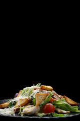 Caesar salad on a black plate. Vertical