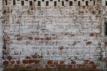 Wall with exposed bricks, in the color of clay, with a light white paint already faded by time.
