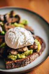 Healthy breakfast from poached egg, smashed avocado, grilled mushrooms on sourdough bread toast, selective focus, shallow DoF