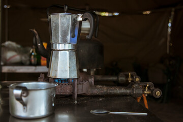 Italian coffee maker and tin cup beside camp stove