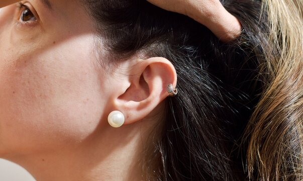 Woman wearing pearl earrings. Earrings at the ear of young woman, women's accessories, gold earrings