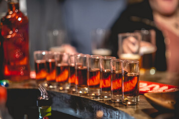 Line of shot glasses with a half of  orange appetizer and a bottle in the bar from a pub