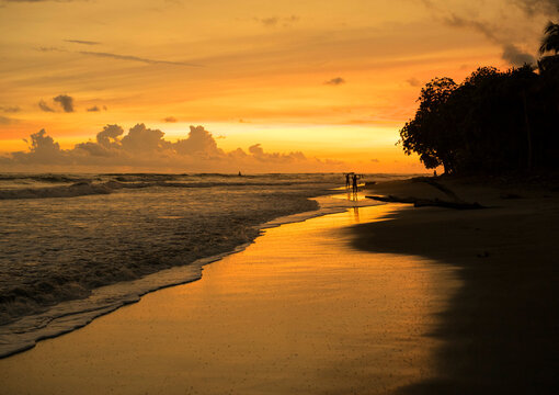 People walking on tropical beach at sunset