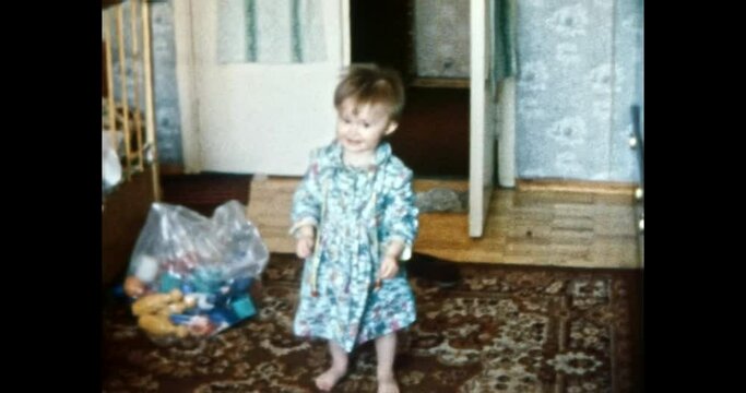 Small child standing in room, smiling. Happy baby in soviet apartment interior, stands on carpet, near toys, laughs, looks at parents. Family life. Vintage color film. Family archive. Retro 1980s. 4k 