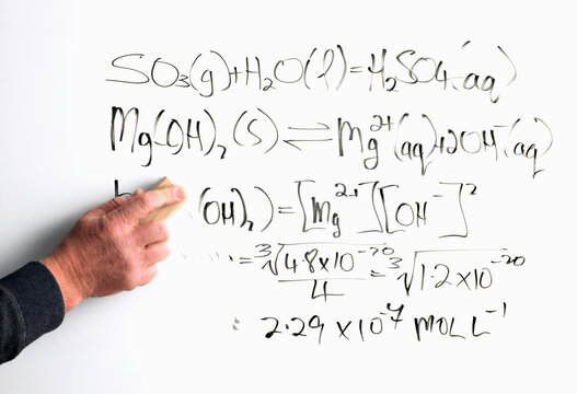 Mans hand rubbing out mathematical equation off the whiteboard