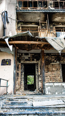 Bucha, Ukraine - May 22, 2022: Russia's aggression against Ukraine. Facade of the building and stairs after tank shots. Destroyed building. Stairs of an abandoned house. House exterior