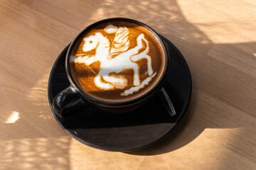 Hot coffee latte with latte art in the form of a horse milk foam in cup mug on wood desk on top...