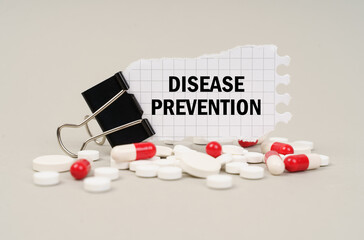 Among the tablets and capsules is a clip with paper on which is written - DISEASE PREVENTION